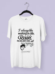 White t-shirt with black text and a graphic of Charlie Chaplin on a hanger against a light purple background